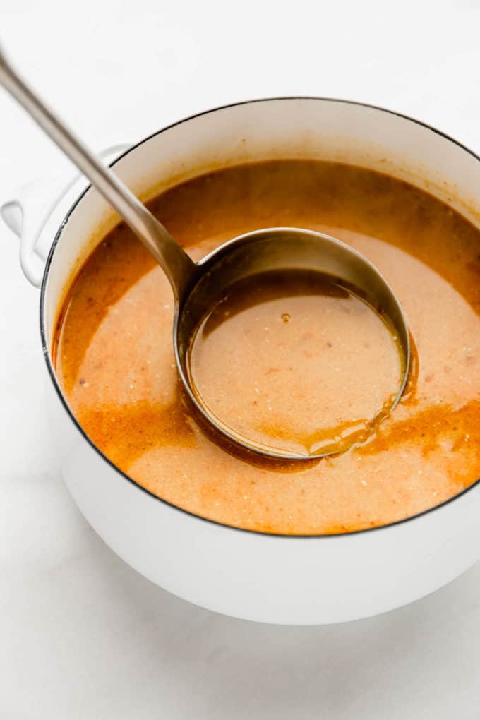A ladle scooping up soup from a pot of Thai Coconut Soup