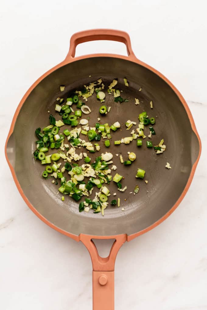 a pan with green onions and garlic in it