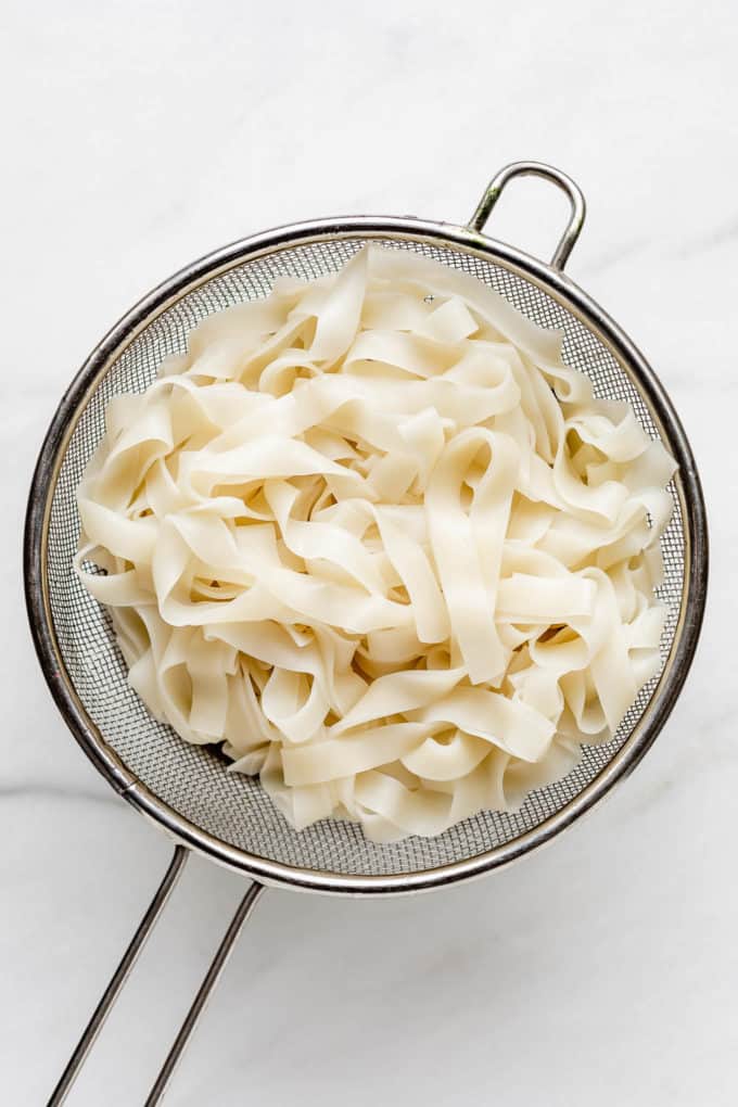 A strainer with rice noodles in it