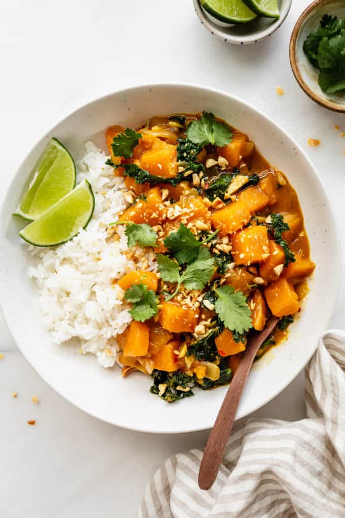 butternut squash curry and rice in a white bowl with a napkin on the side