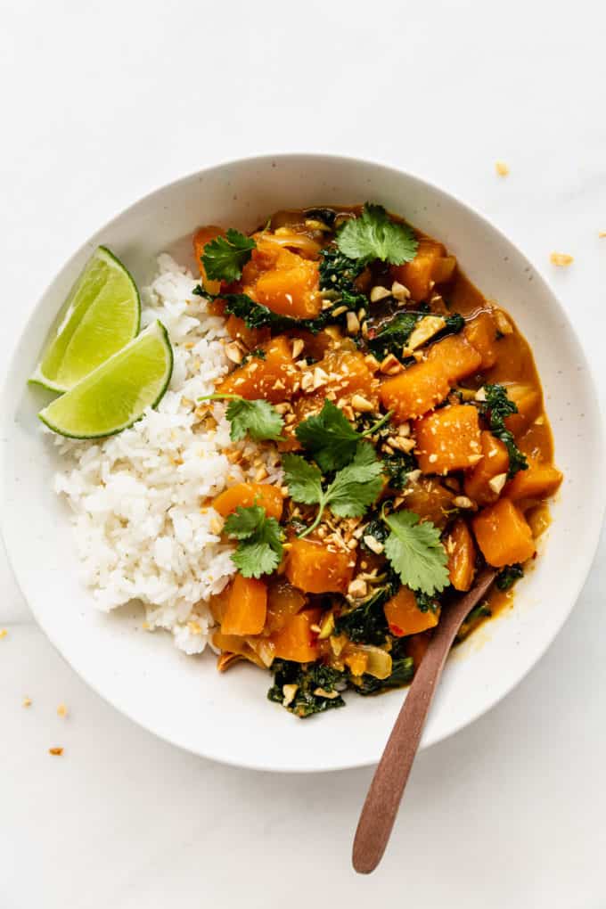 A bowl of butternut squash curry topped with cilantro and a lime wedge