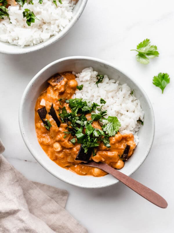 A bowl of eggplant curry with rice topped with cilantro