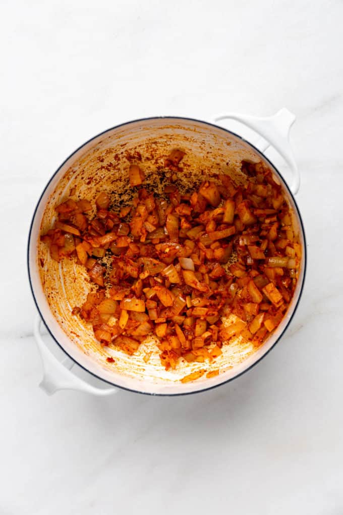 A pot with onions, garlic and spices in it