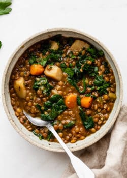 lentil stew in a bowl with a brown napkin on the side