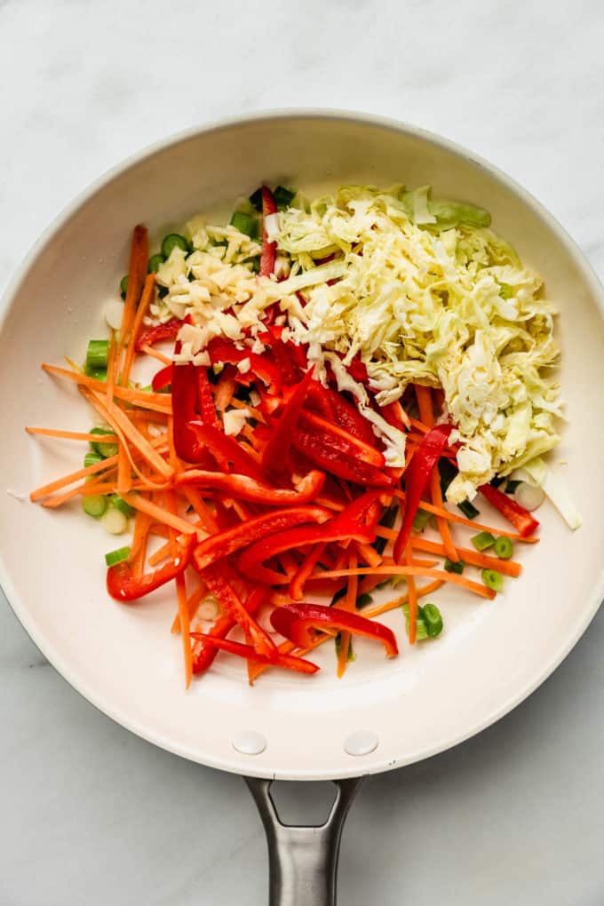 A white pan with peppers, carrots and cabbage in it