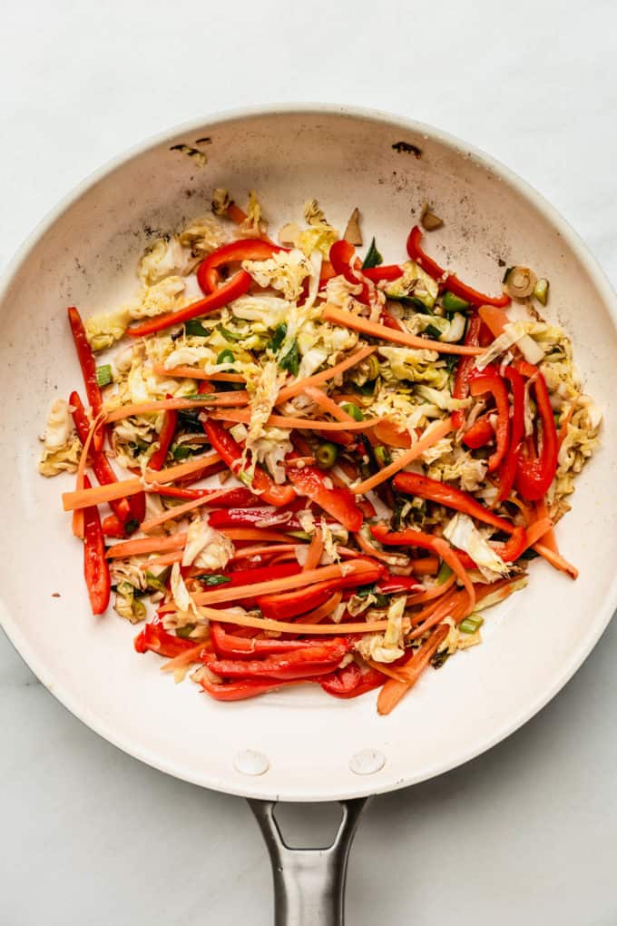 A white pan with stir fried vegetables in it