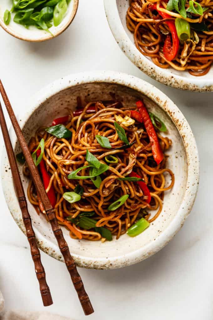 A bowl of vegan chow mein with chopsticks on top