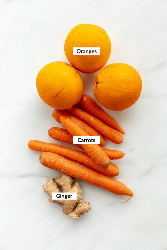 oranges, carrots and ginger on a marble board
