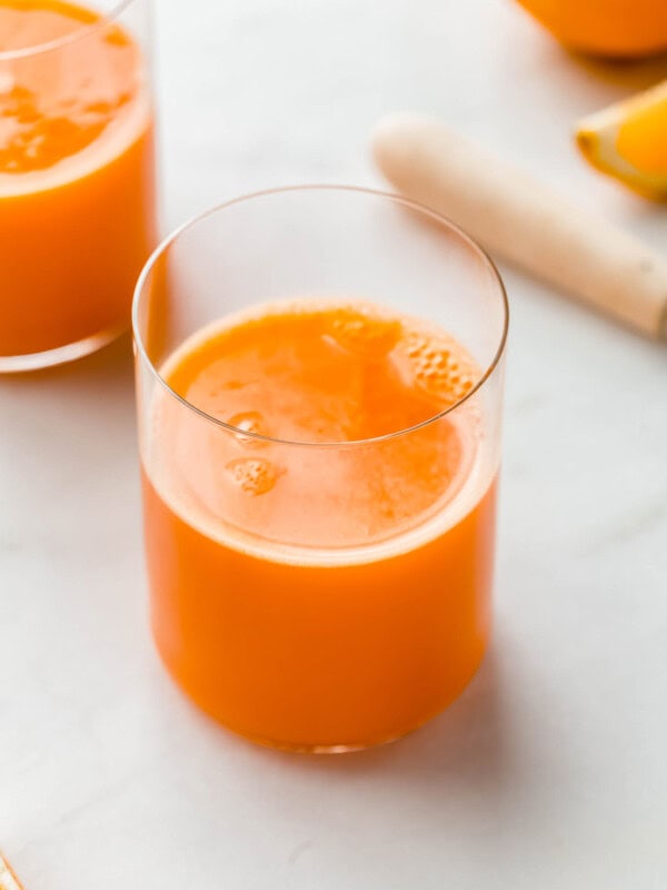 A cup of immune boosting orange and carrot juice with oranges in the background