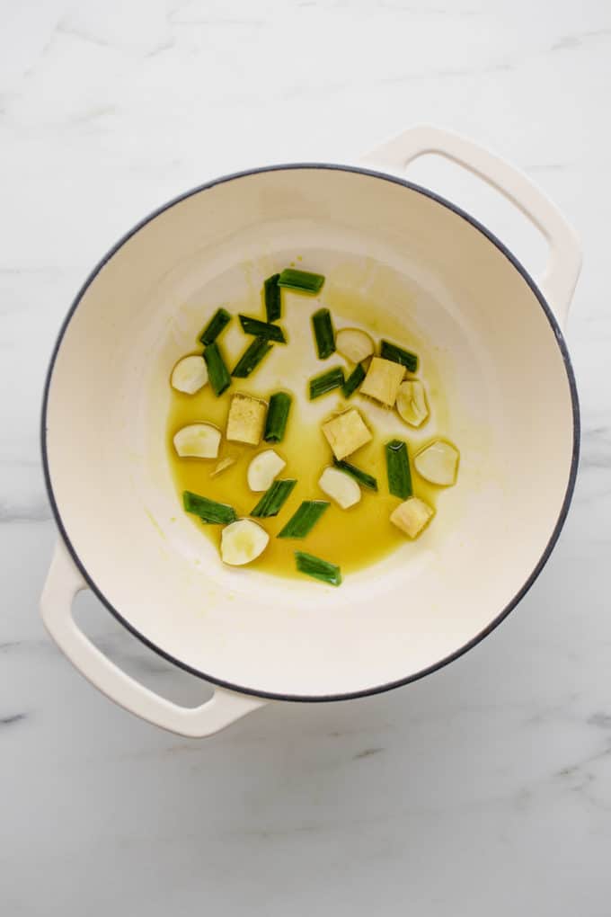 Garlic, ginger and green onions in oil in a white pot