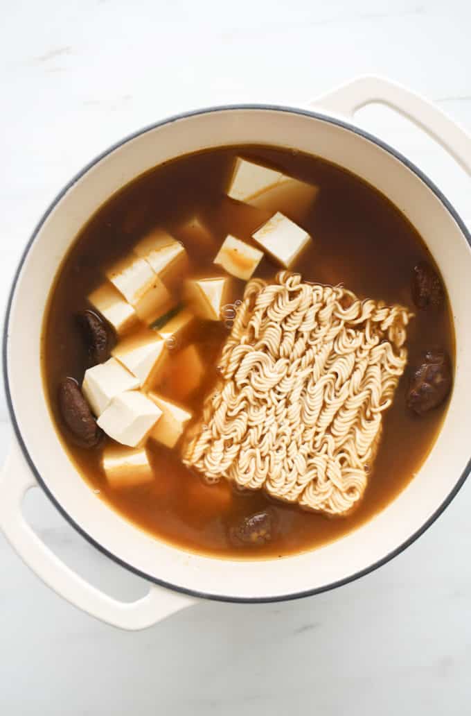 Vegan ramen soup with tofu and ramen noodles in a white pot