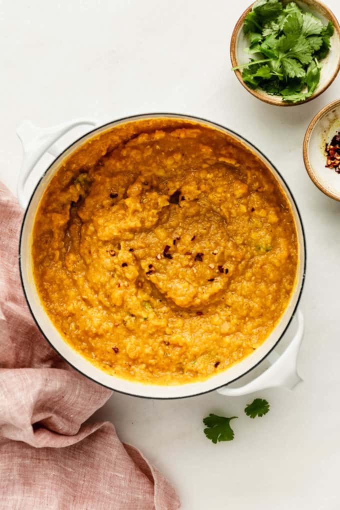 Red lentil dahl in a white pot with a pink napkin on the side