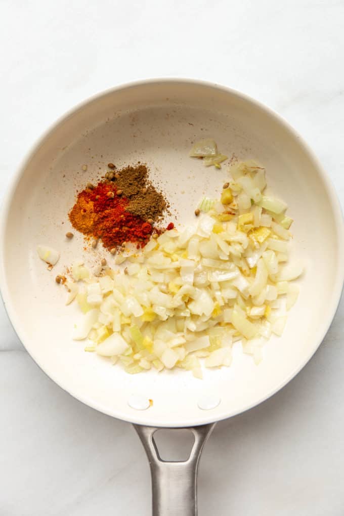 a white pan with onions and spices in it