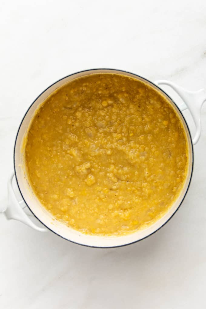 A white pot with cooked red lentils in it