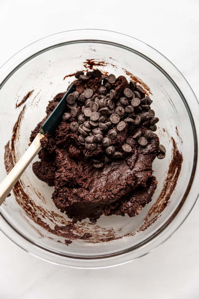 A mixing bowl with brownie batter and chocolate chips in it