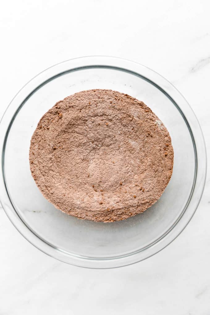 A clear mixing bowl with a mix of flour and cocoa powder in it