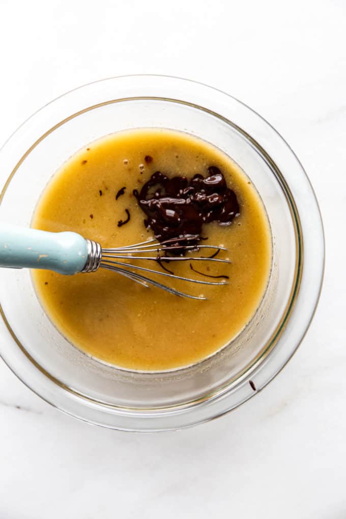 A bowl with vegan butter and chocolate in it with a whisk