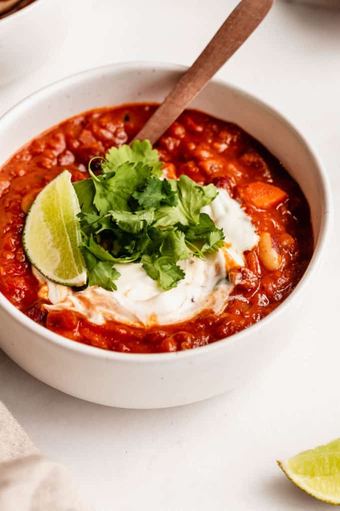 vegan chili topped with cilantro and lime in a white bowl