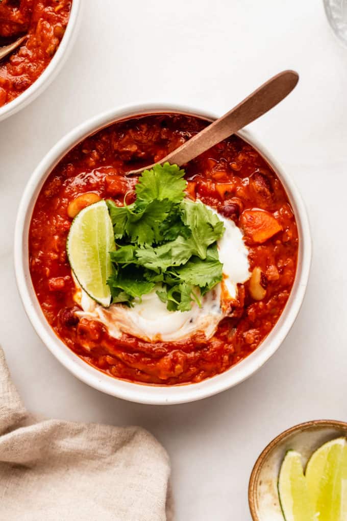 a bowl of vegan chili with sour cream and cilantro on top