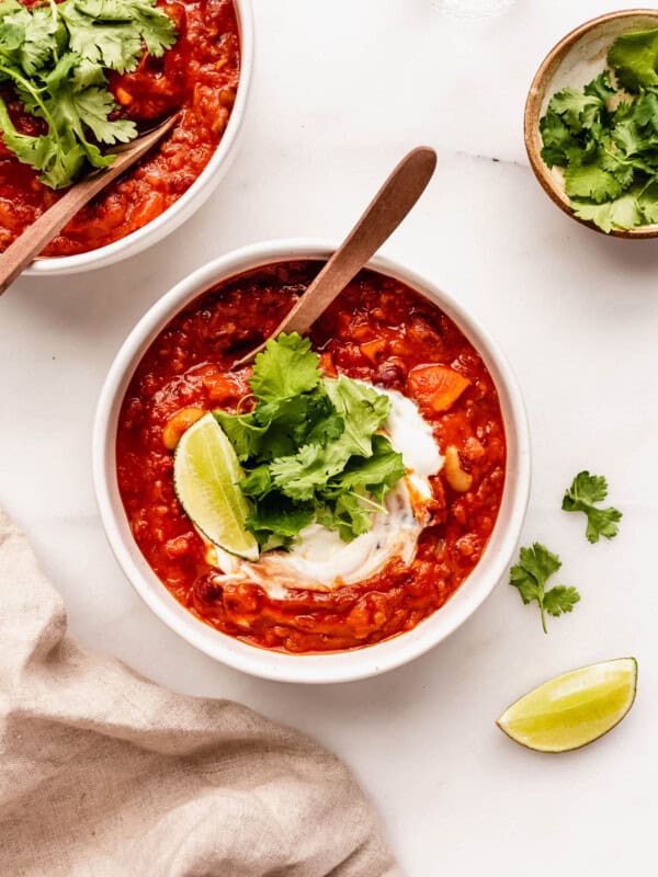 two bowls of vegan chili topped with cilantro with spoons in them