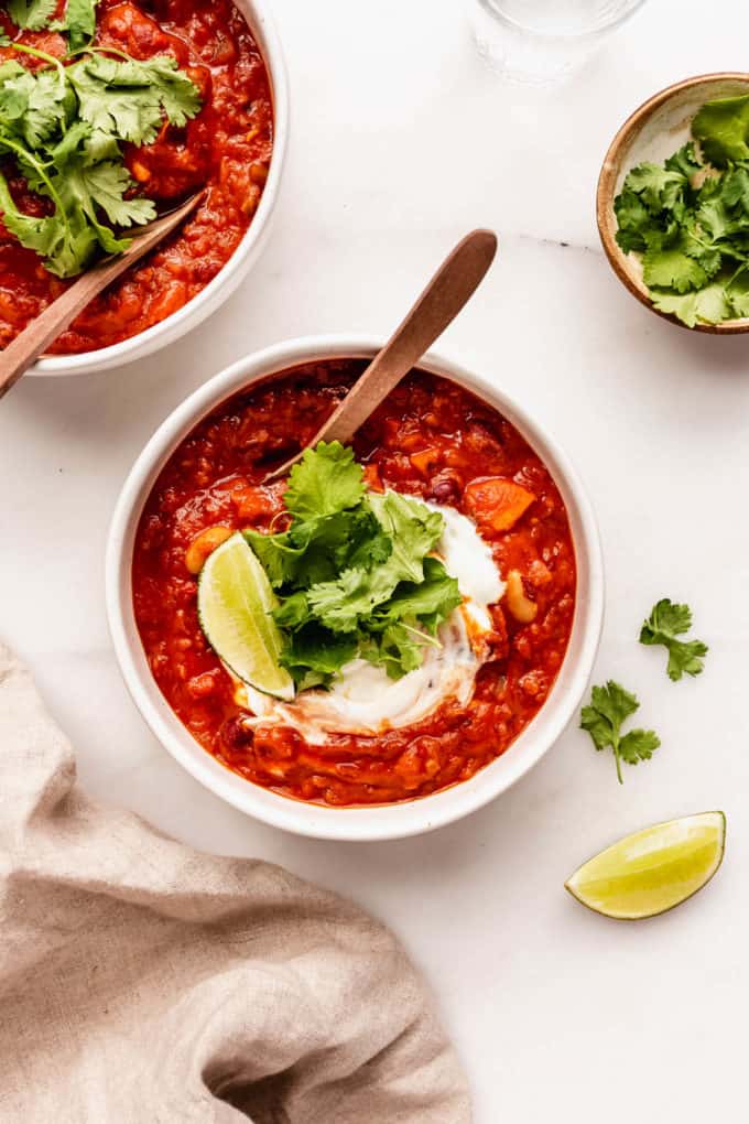 two bowls of vegan chili topped with cilantro with spoons in them