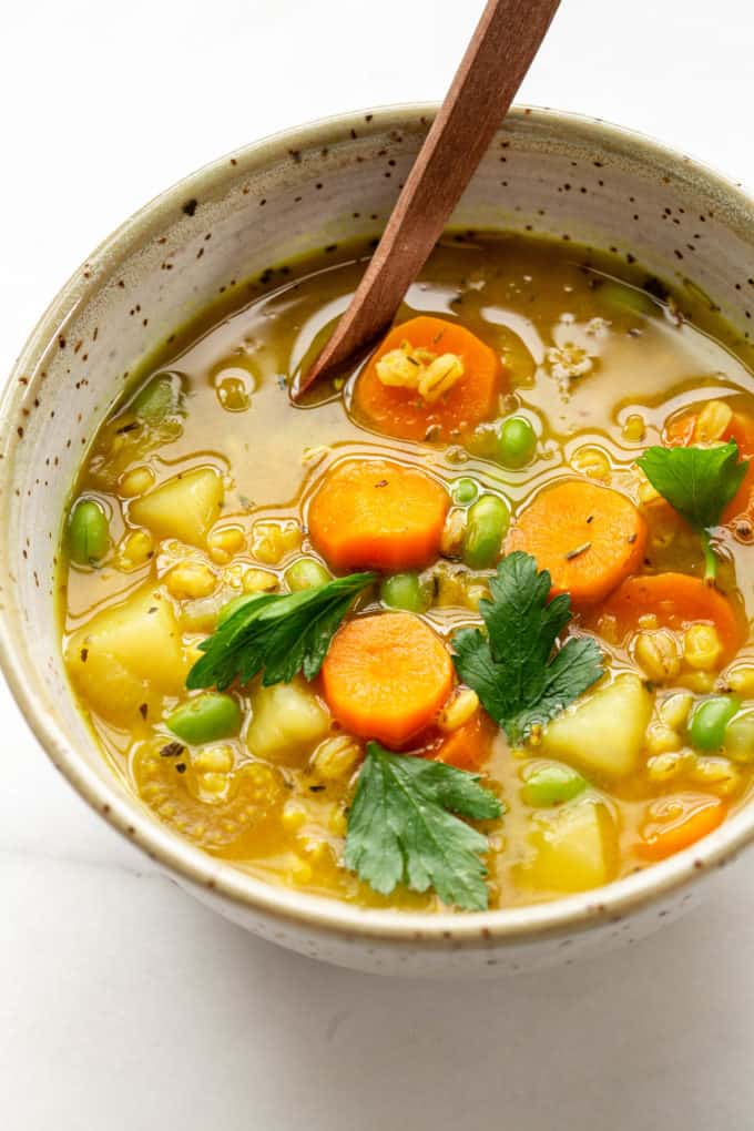 Vegetable barley soup in a speckled bowl