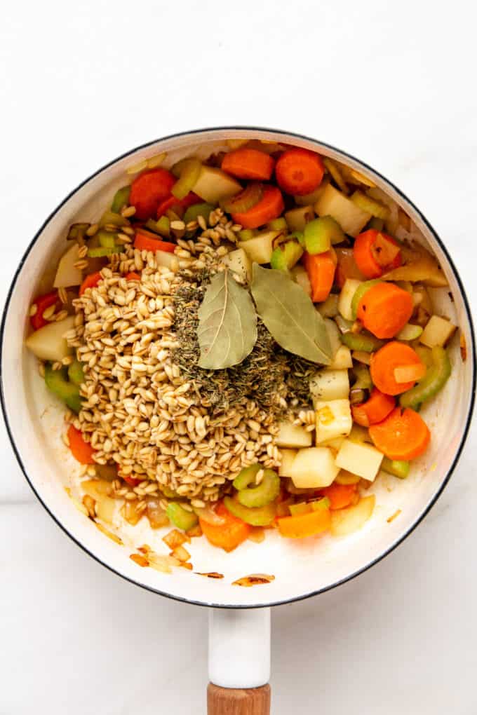 vegetables, dried barley and bay leaves in a pot
