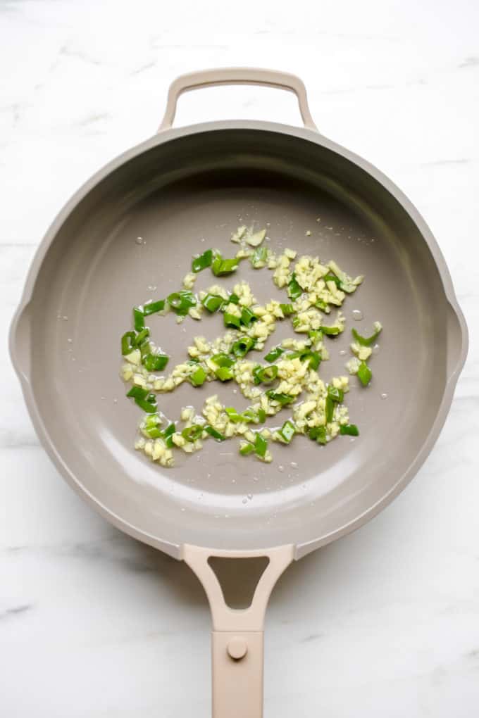 A pan with garlic, ginger and green onions in it
