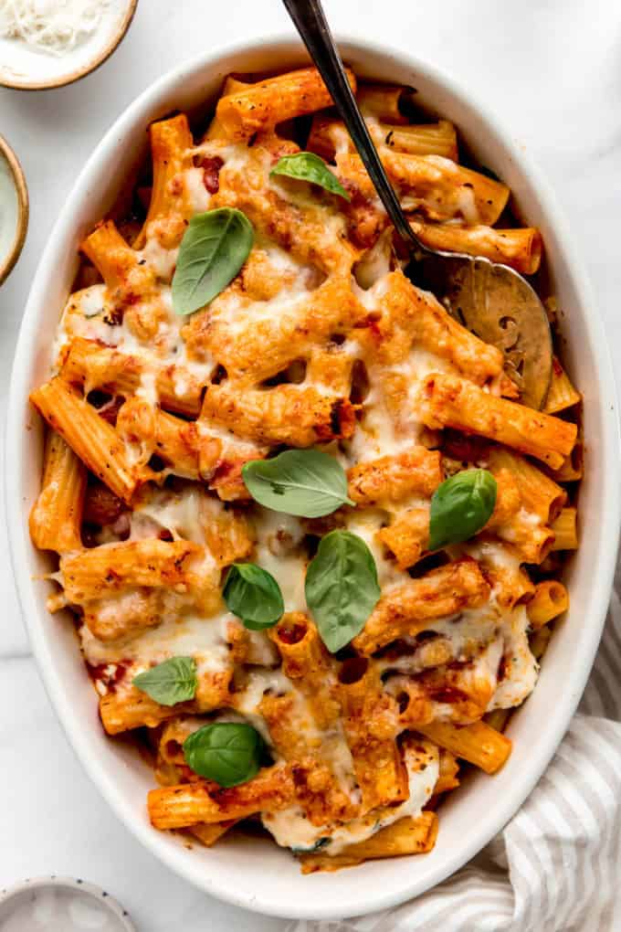 baked ziti in an oval baking dish with a serving spoon in it
