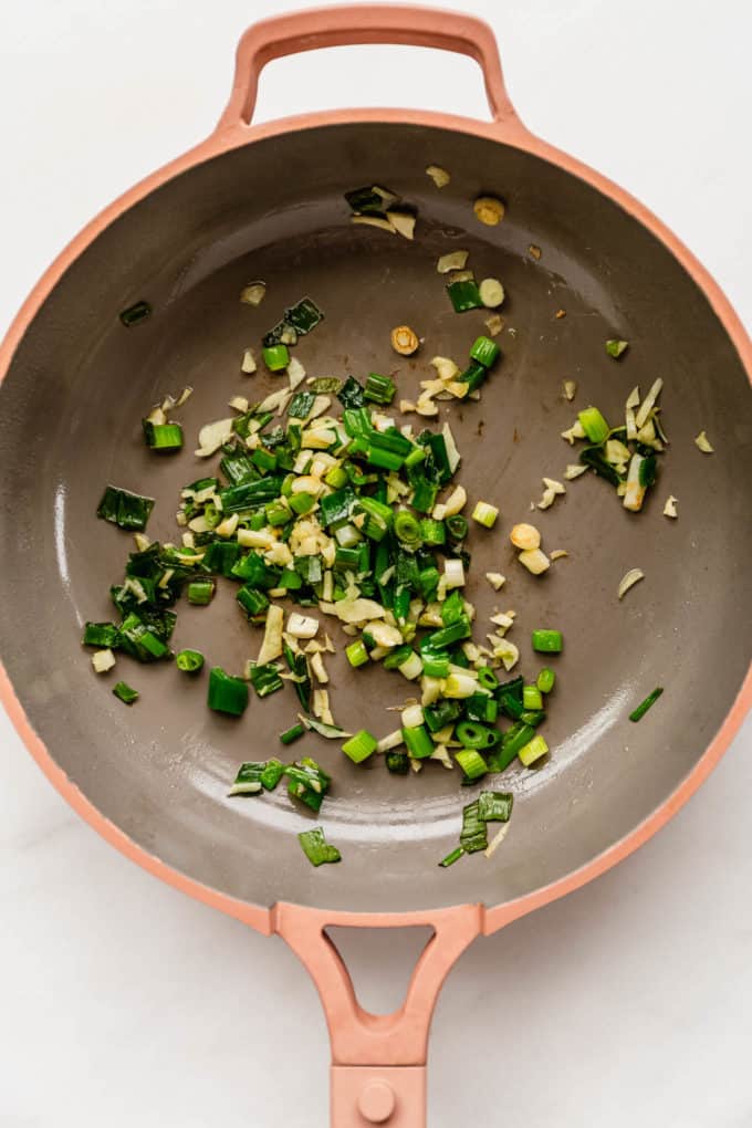 scallions and garlic in a pink pan