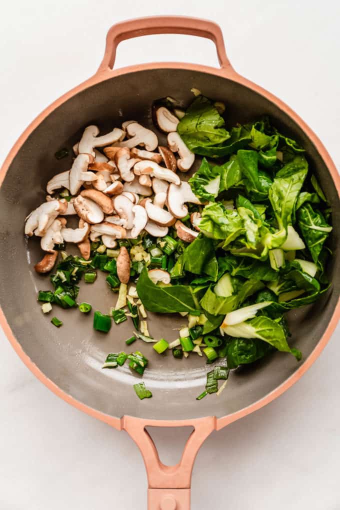 bok choy and shitake mushrooms in a pink pan