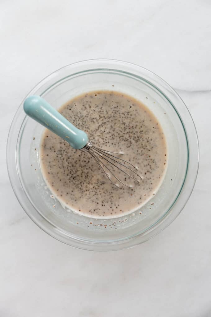 eggnog and chia seeds in a mixing bowl with a whisk
