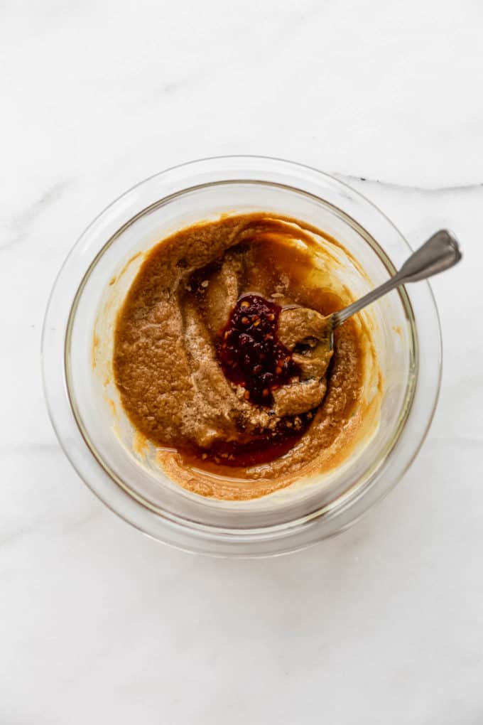 A mixing bowl with peanut butter, soy sauce and sambal oelek in it