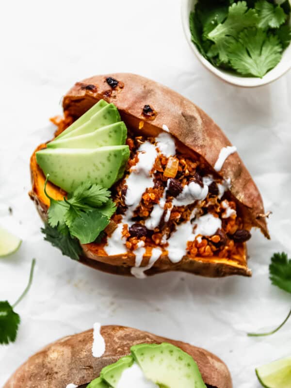 A black bean and quinoa stuffed sweet potato with sour cream and avocado on it