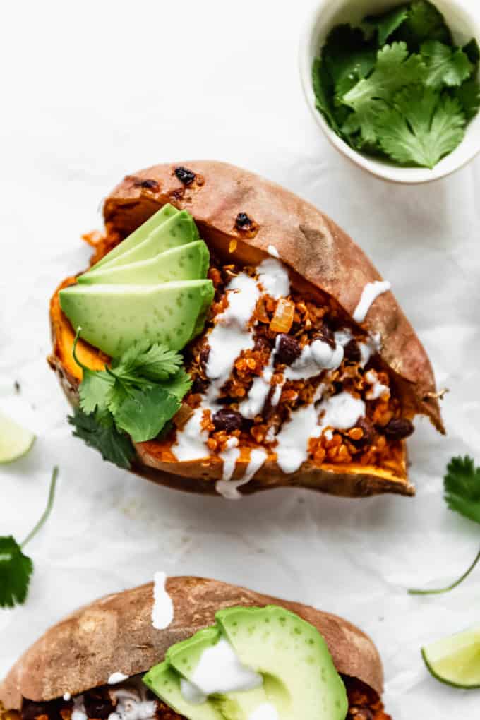 A black bean and quinoa stuffed sweet potato with sour cream and avocado on it