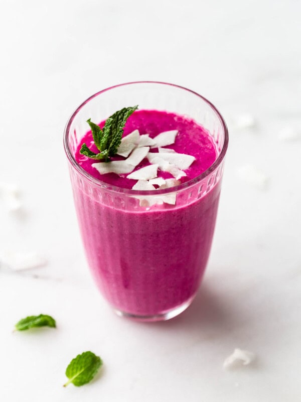 a dragon fruit smoothie in a glass topped with coconut flakes