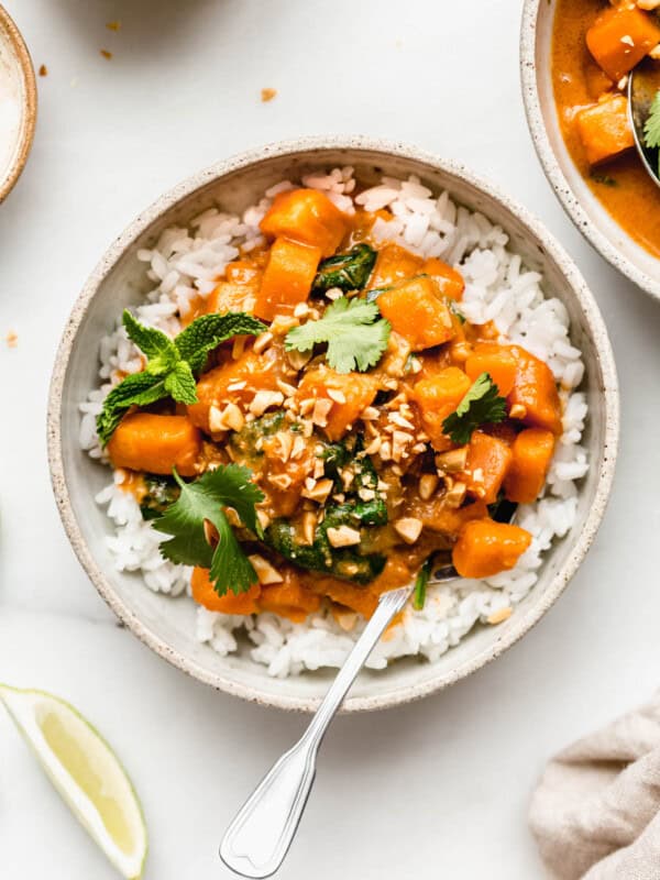 a bowl of sweet potato curry over rice with crushed peanuts on top