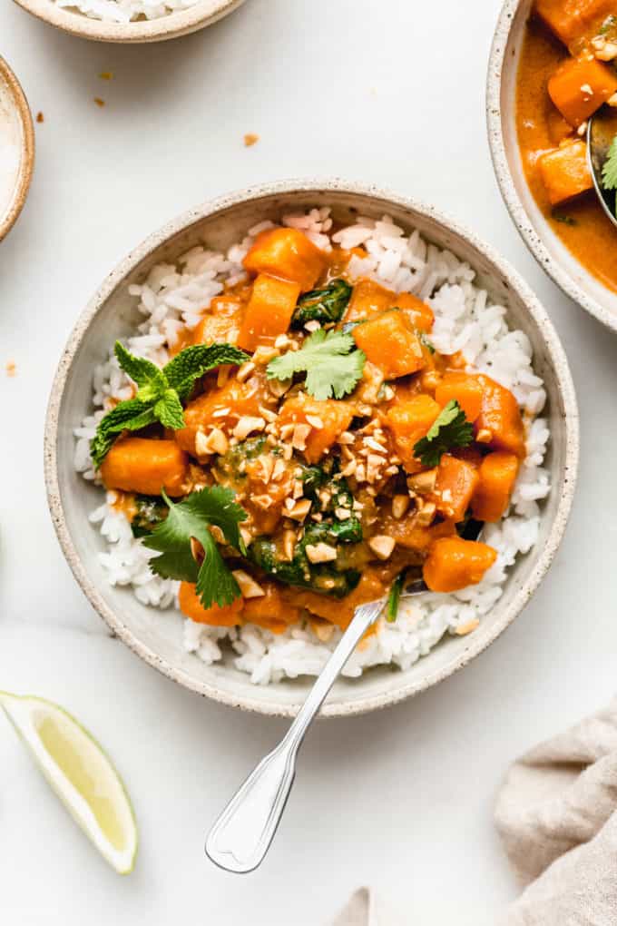 a bowl of sweet potato curry over rice with crushed peanuts on top