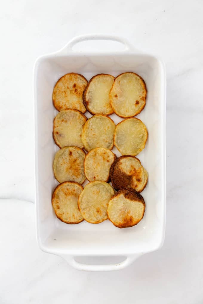 sliced potatoes layered in a baking dish