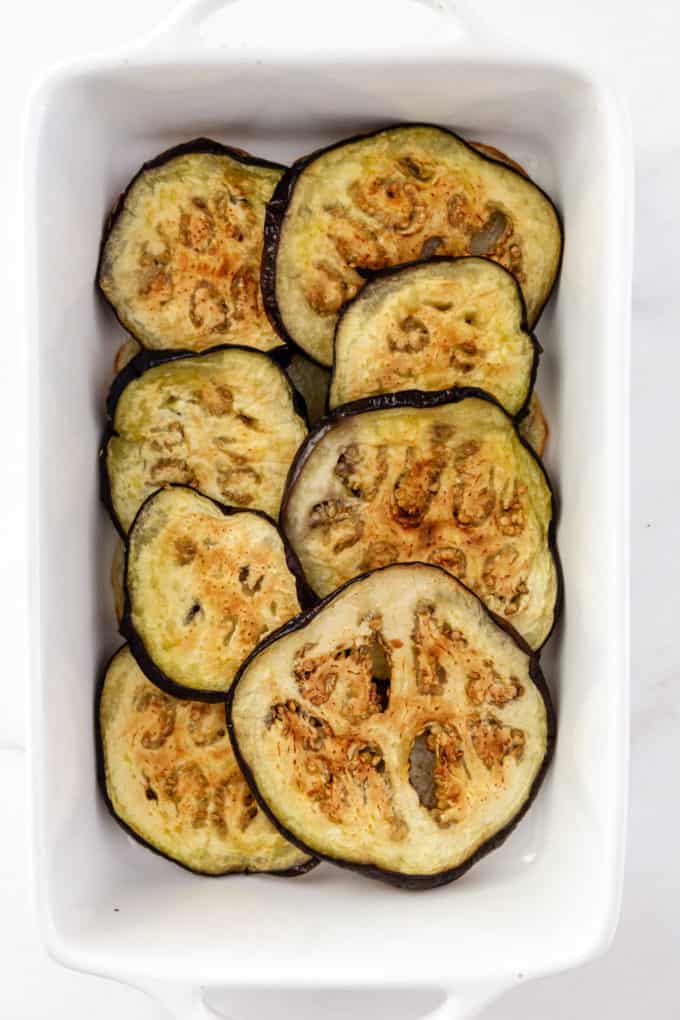 sliced roasted eggplant layered on a baking dish