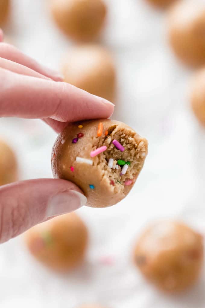 a hand holding a protein ball with a bite taken out of it