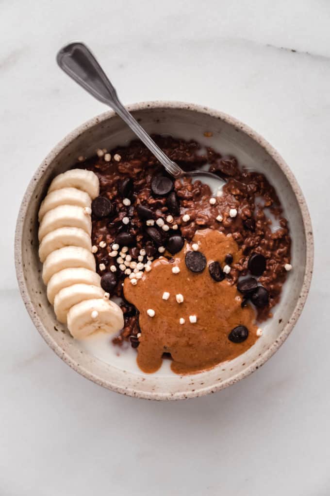 a bowl of chocolate oatmeal topped with banana and nut butter