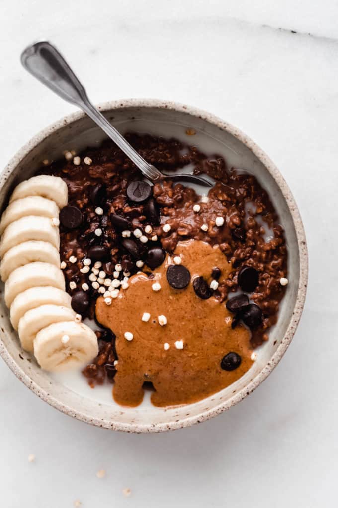 Chocolate oatmeal topped with chocolate chips, almond butter and sliced bananas