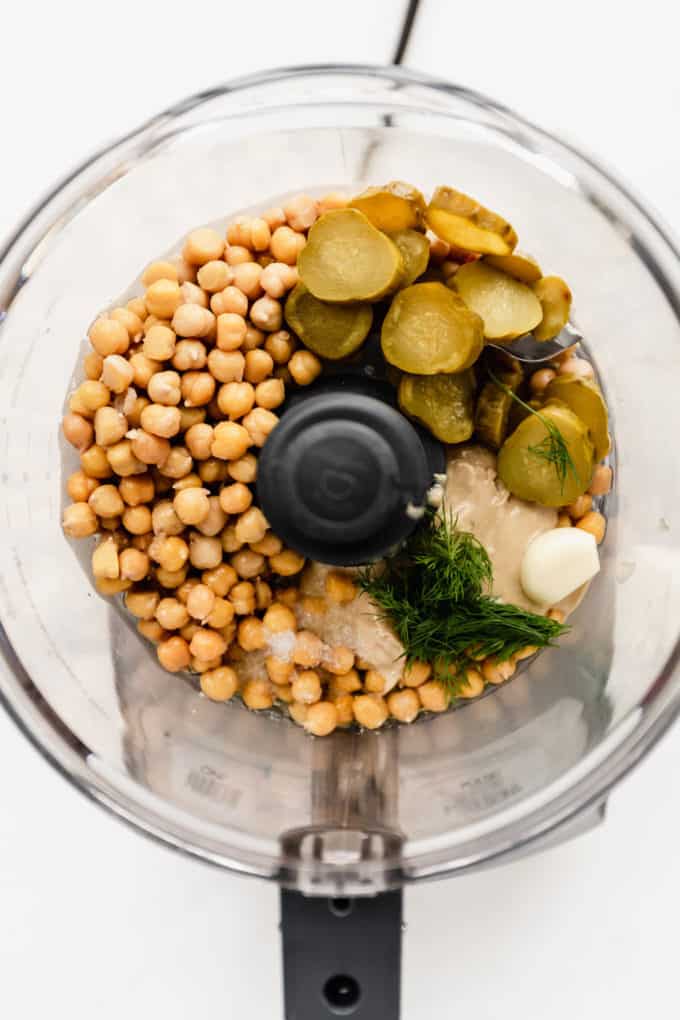 a food processor with chickpeas and pickles in it