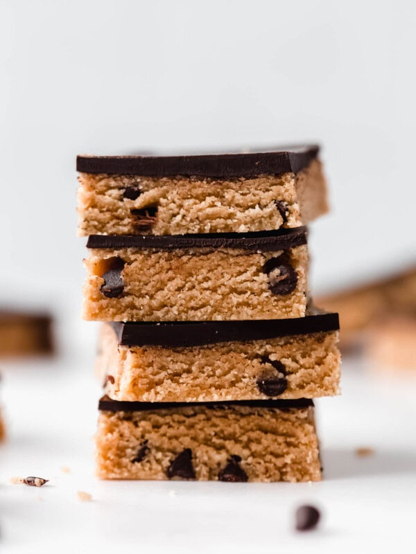 a stack of cookie dough bars topped with dark chocolate