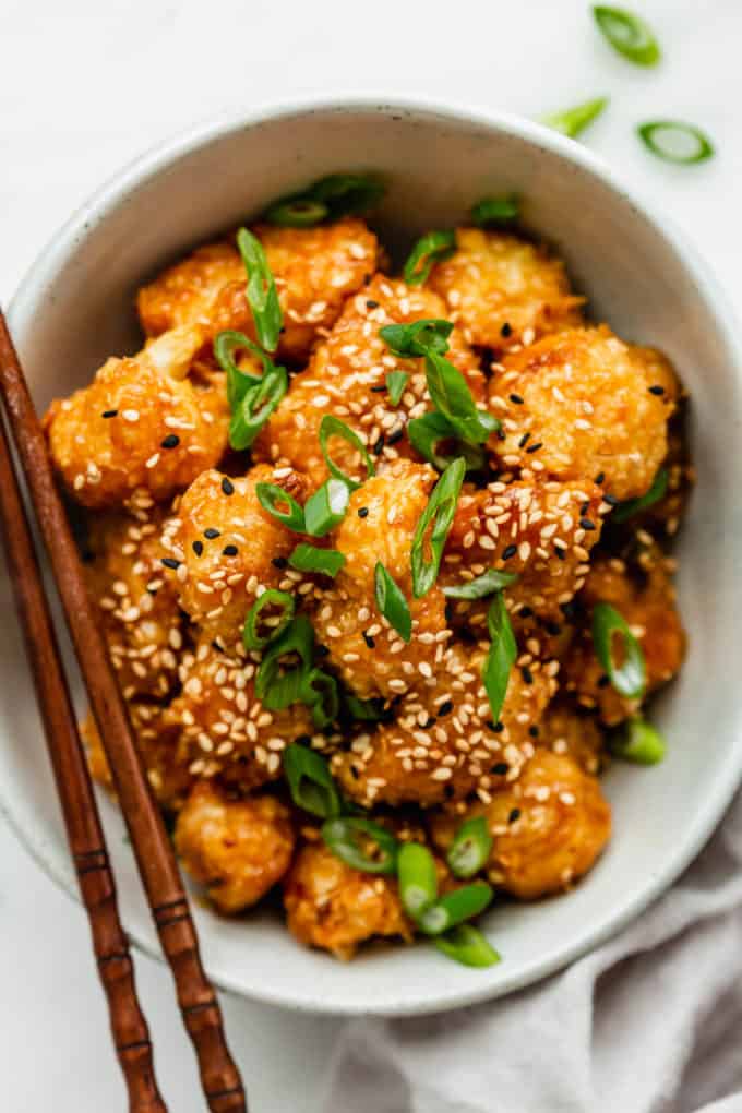 Orange cauliflower in a bowl with chopsticks on the side