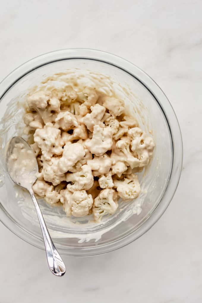 cauliflower florets tossed in a bowl of batter