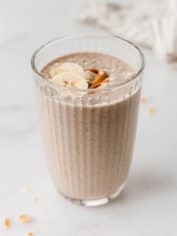 Peanut butter banana smoothie in a glass topped with banana