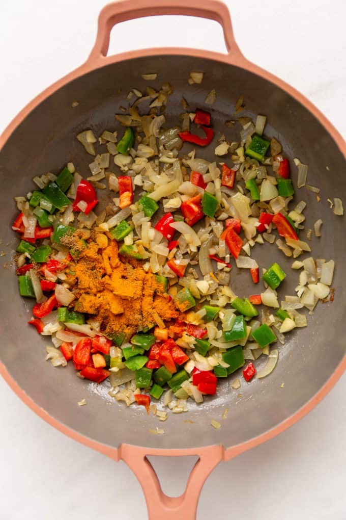 Sauteéd peppers and onions in a pan with spices