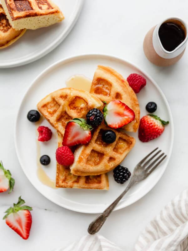 A plate of almond flour waffles topped with strawberries, blackberries, blueberries and raspberries